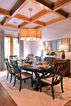 a dinning room table and chairs in front of a large window with wooden beams