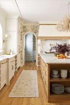 a kitchen with wooden floors and white walls, along with an area rug on the floor