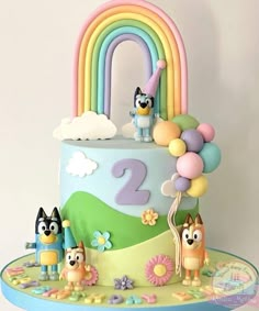 a birthday cake is decorated with cartoon characters and rainbows in the shape of numbers