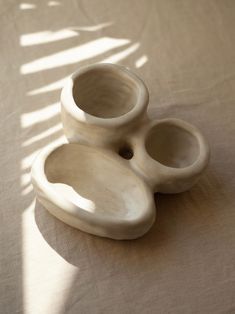 two white vases sitting on top of a table next to each other in front of a window