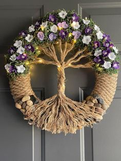 a wreath decorated with flowers and lights hanging on a door frame in the shape of a tree