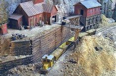 an aerial view of a model train set with buildings and mountains in the background,