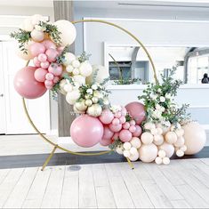 balloons and greenery are arranged in the shape of an o - ring on a floor