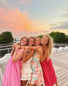 three girls hugging each other on a wooden deck