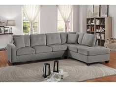 a gray sectional couch sitting on top of a rug in a living room next to a window