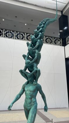 a sculpture in the middle of a building with people climbing up it's sides