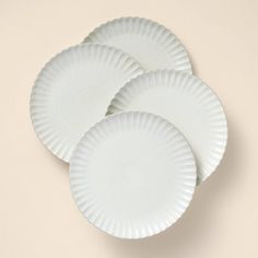 three white paper plates sitting next to each other on top of a beige tablecloth