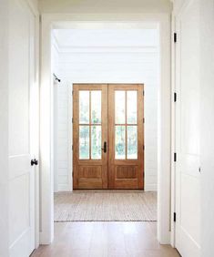 two wooden doors are open on the inside of a white room with wood flooring