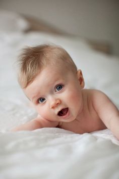 a baby laying on top of a white blanket