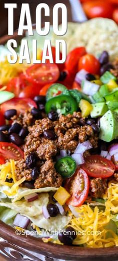 taco salad in a bowl with lettuce, tomatoes, black beans and cheese