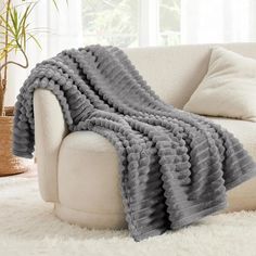 a white couch with a gray blanket on it