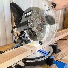 a person using a circular saw to cut a piece of wood on top of a table