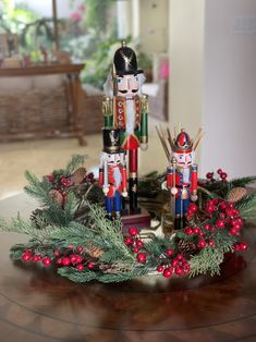 two nutcrackers are sitting on top of a table with berries and pine cones