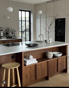 a kitchen island with two stools and a vase on it in front of a window