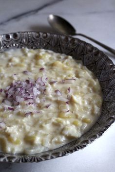 a bowl filled with oatmeal and red onions on top of a table