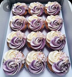 a box filled with lots of cupcakes covered in purple and white frosting