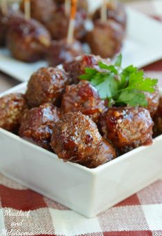 meatballs with parsley in a white bowl on a red and white checkered tablecloth