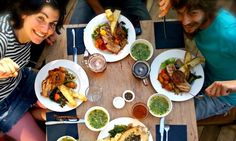 three people sitting at a table with plates of food