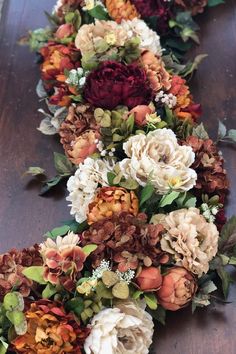 an arrangement of flowers arranged on a wooden table in the shape of a long ribbon