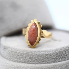 Unique vintage 14k yellow gold goldstone glass ring, circa 1940s! This beautiful flower inspired statement piece showcases a glittering goldstone glass center, which is marquise cabochon cut. The setting is adorned with two leaf design gold plaques and the ring head a scalloped border. A full bezel secures the goldstone glass. A fabulous piece of fine Retro Era floral jewelry, from the fabulous '40s! *Sale - price reduced from $495 USD to $485 USD. ERA - Circa 1940s, Retro METAL / MATERIAL - 14k Gold Art Deco Ring With Cabochon, Art Deco Gold Cabochon Ring, Vintage Untreated Yellow Gold Rings, Mid-century Gold Jewelry With Cabochon, Mid-century Gold Cabochon Jewelry, Untreated Vintage Yellow Gold Rings, Vintage 14k Gold Oval Cabochon Jewelry, Vintage Marquise Gemstone Jewelry, Vintage Marquise Jewelry For Gifts