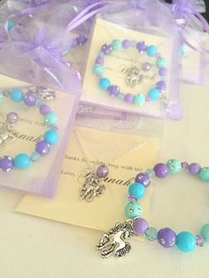 three bracelets with charms on them sitting on a table next to each other in plastic bags