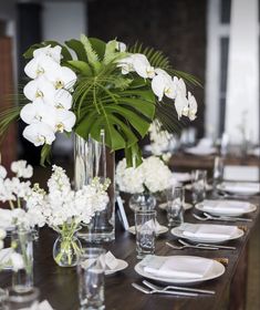 the table is set with white flowers and place settings