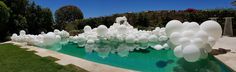 an artificial water feature in a backyard pond with clear blue water and white balloons floating on the surface