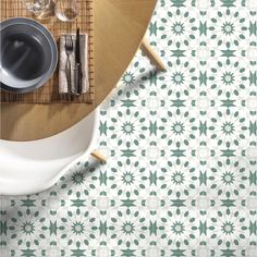 a table with plates and silverware on it, next to a bamboo mat that has green leaves