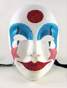 This handcrafted, full face, Venetian volto mask is decorated in shimmering sky blue, red, and rose pink glitter with a white painted face.  The mask is handmade from paper mache and measures approximately 9" high, 6 ½" wide and 3 ½" deep. The mask has traditional black ribbon ties for a comfortable fit.  All masks are handmade in Venice, Italy. No two masks are ever identical. Colors and patterns may vary slightly on each mask. Fun White Masquerade Masks, Volto Mask, Stripe Mask, Costume Masks, Painted Face, Glitter Stars, Ribbon Tie, Red Glitter, Black Ribbon