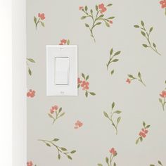 a white light switch sitting on top of a wall next to a flowery wallpaper