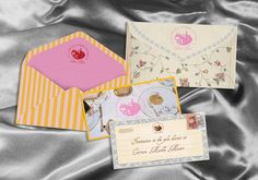 three envelopes are laying on top of a satin material surface, one is pink and the other is yellow