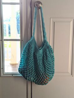 a crocheted bag hanging on a hook in front of a door with a window