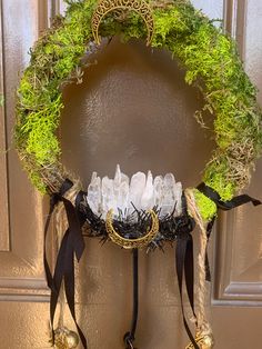 a wreath that is hanging on the front door with some glass bottles and bells attached to it