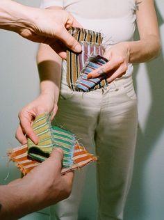 two people are holding small pieces of fabric