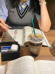 a woman sitting at a table with an open book and coffee in front of her