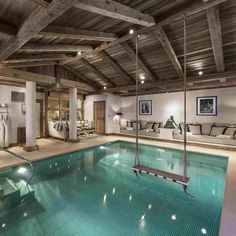 a large indoor swimming pool in the middle of a room with wooden ceilinging and exposed beams