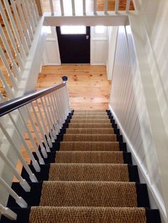 the stairs are made of wood and have white railings with black handrails