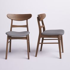 two wooden chairs side by side, one with grey upholstered seat and the other without