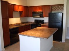 an empty kitchen with black appliances and brown cabinets