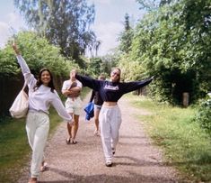 two women walking down a dirt road with their arms in the air and one holding her hands up