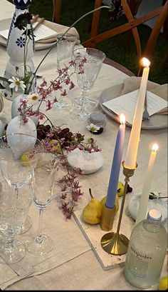 the table is set with wine glasses, candles and flowers in vases on it