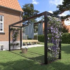 an outdoor area with a bench, table and flowers in the grass near a brick building