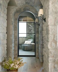 an arched doorway leading to a living room with a couch and chair in the corner