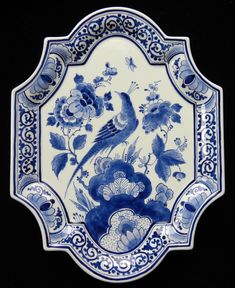 a blue and white plate with flowers, birds and butterflies on it's side