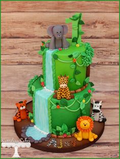 a three tiered cake with jungle animals on top and green fondant icing