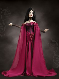 a doll with long black hair wearing a pink dress and holding a stick in her hand