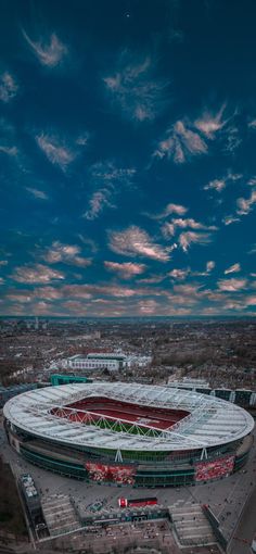 an aerial view of the soccer stadium in england at dusk with clouds and blue sky