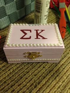 a box with pearls and letters on it sitting next to a pair of scissors, pencils and other crafting supplies