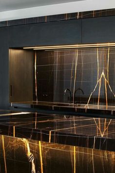 a kitchen with black and gold marble countertops, stainless steel appliances and cupboards