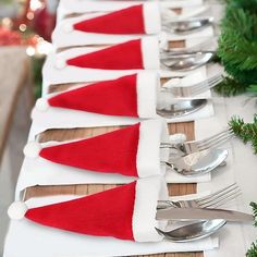 a long table with silverware and santa hats on it